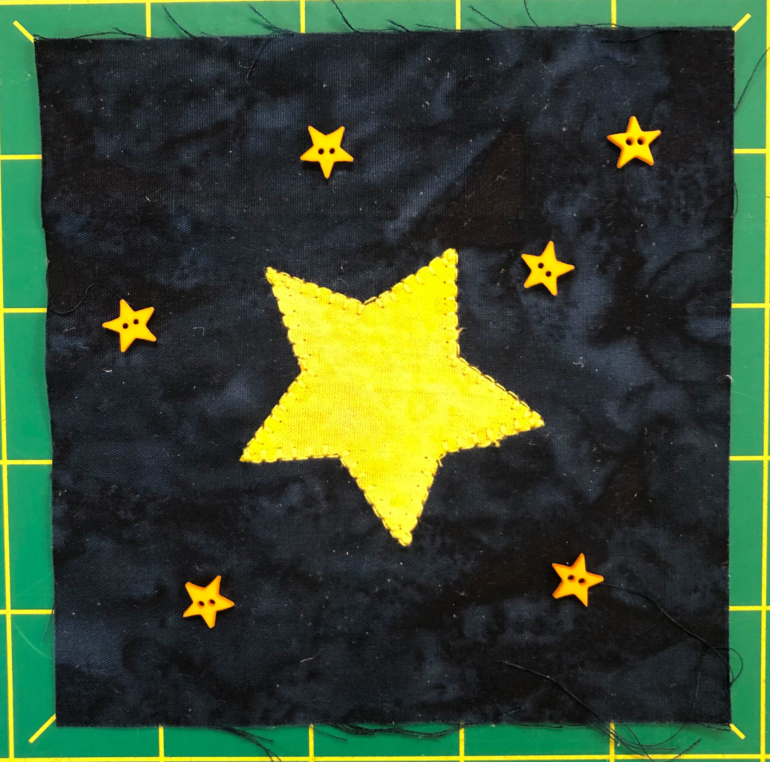 Fabric quilt block of stars with a big star in the middle.