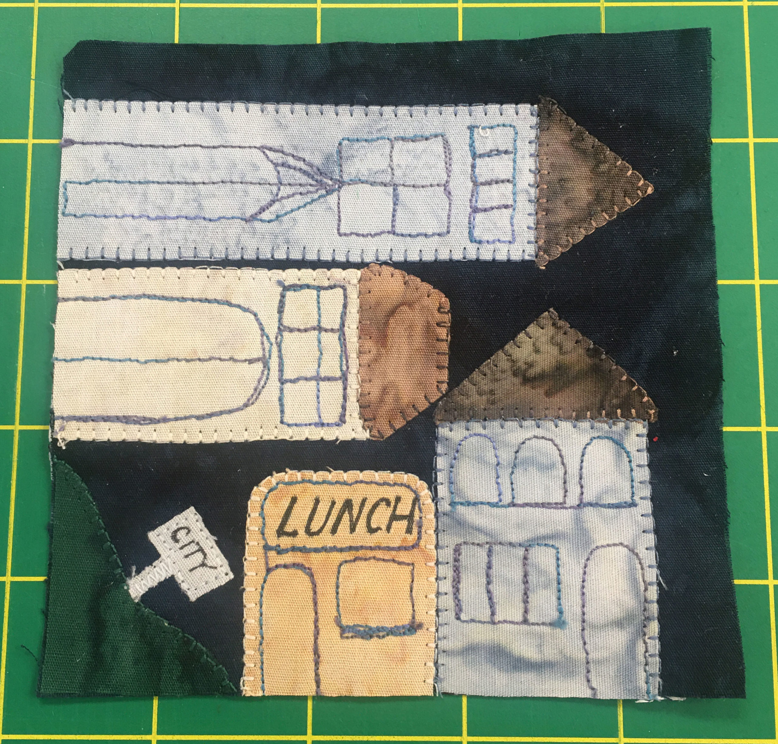 Buildings are placed across the breadth of a quilt square both horizontally and vertically as they go around a corner. A sign reading