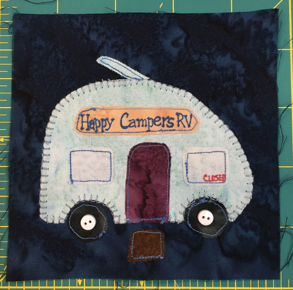 This quilt block shows an RV camper with a sign on it reading,