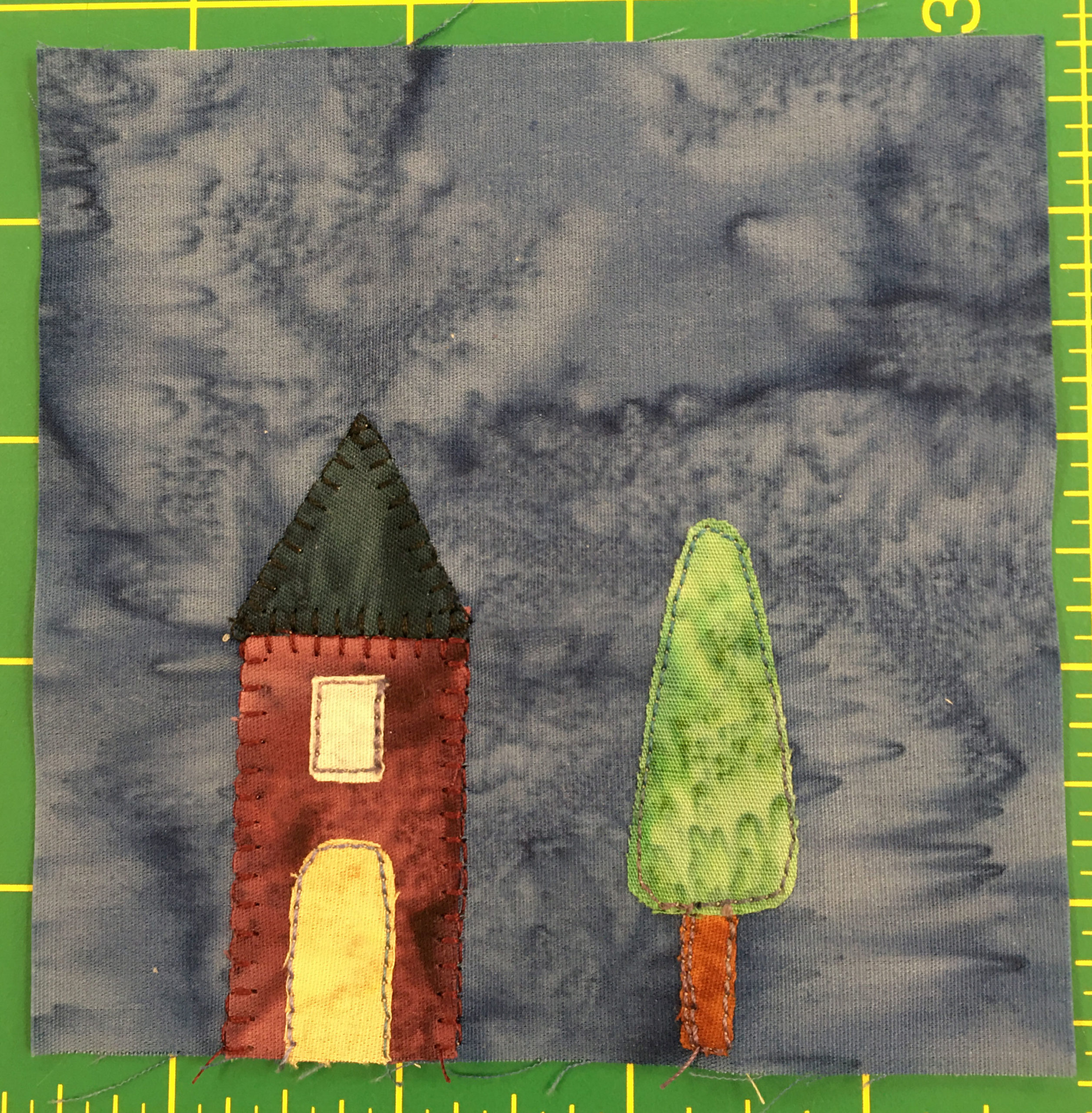 This block shows a lighter gray background rather than blue. There is a small narrow house with a window abot the door on the left, and a singular tree on the right.