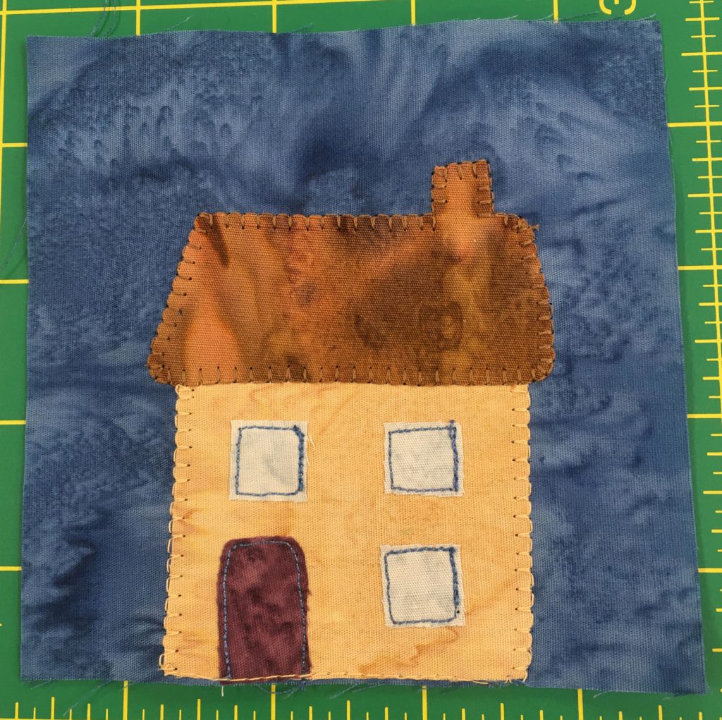 This block shows a simple two story yellow house with three square windows, one below and two above. There is a maroon door on the left, and a brown roof with a chimney on the right.