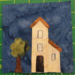 This is an awkward light orange vuilding. One side is two stories, while the right side is one story and looks attached like a studio. To the left of the building is a tree.