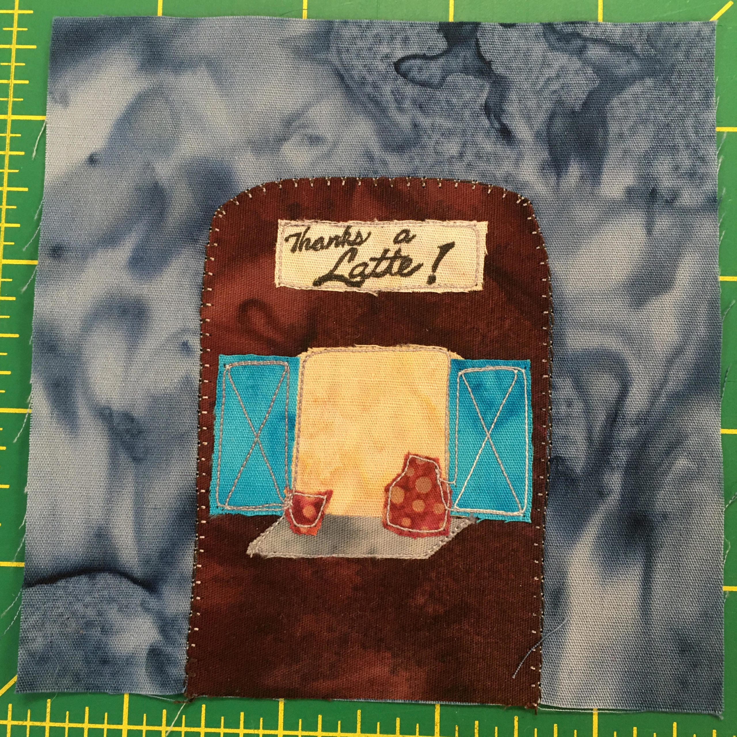 This quilt block shows an enclosed coffee stand. On the front is a big window that's open with two blue door 