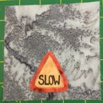This quilt block is simple. It has a gray multi-shaded background with a triangular traffic sign that reads, 