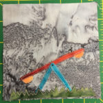 This quilt block shows a see-saw or teeter-totter from the side. This supports are in a light blue fabric, while the see-saw itself is the same burnt orange the other playground equipment was in. On the bottom of each end is a yellow 