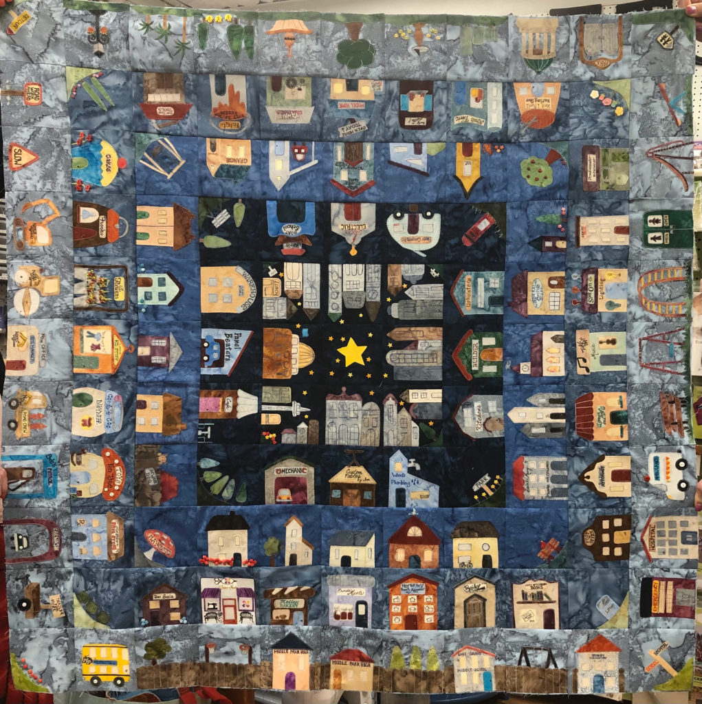 This shows the quilt as it's constructed so far. There are five rounds and a center square featuring a star. As each square round progresses outward the background gets lighter, as if the sun is rising.