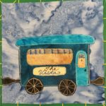 This quilt block shows a very blue railroad car against a faded blue salmon-patterned background. The roof is a bright light blue as well as the door. The rest of the rectangular car is a darker blue. The windows, one in the door and a large single window on the side are a dark orange-yellow. There are drapes in the windows that are pulled up defined by a blue pen drawing. There is a sign underneath the larger window that reads in cursive, 