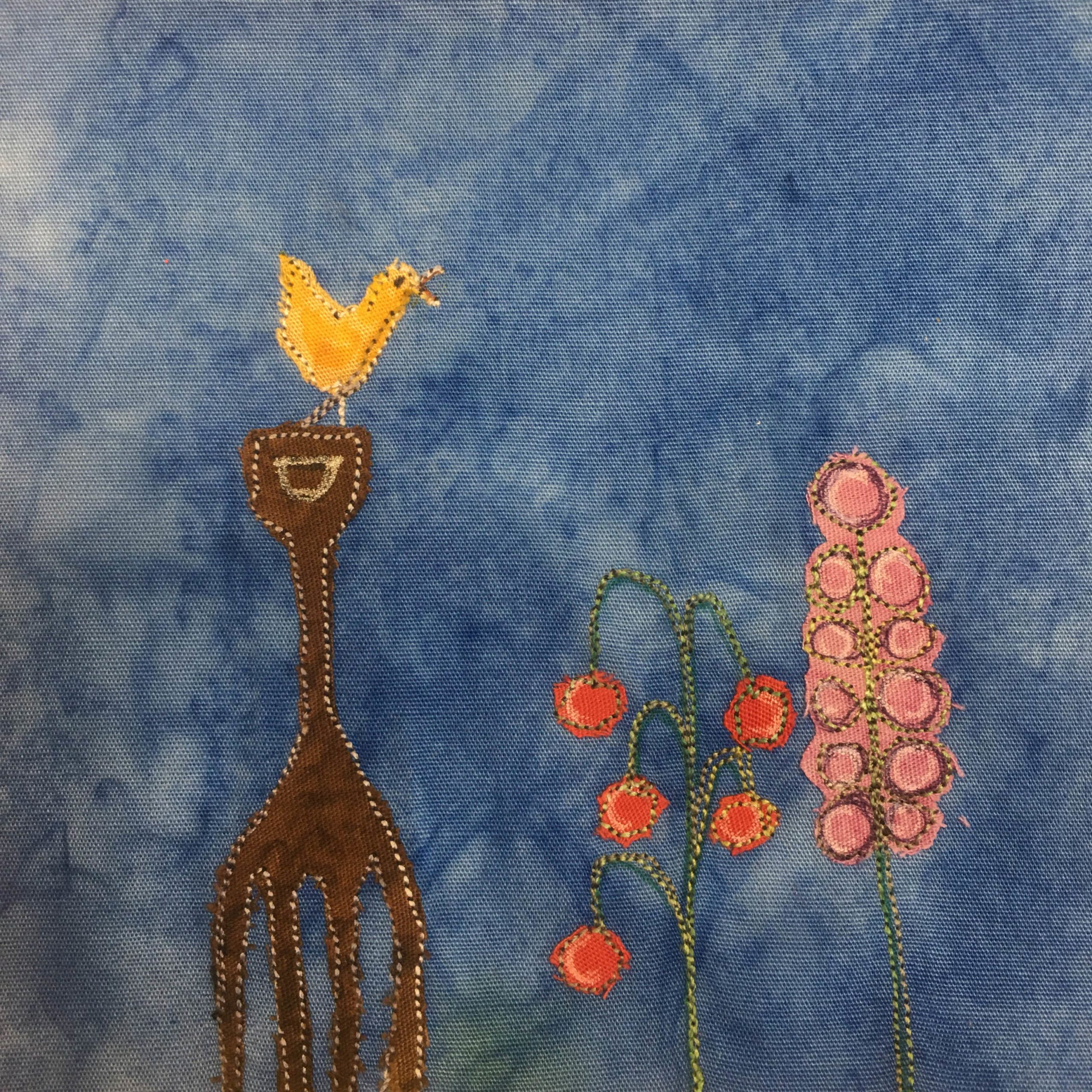 This block shows a brown garden fork sticking in the ground. It's like a pitch fork but it's completely brown and made of wood. It's fairly large. On top of the fork is a yellow singing bird. Next to the fork are two beautiful plans, drawn by green pen and stitching. Each flower has bulbs on the ends, one in a drooping fashion that are red, and the other along the stalk going up that are pink. This is all against a blue background.