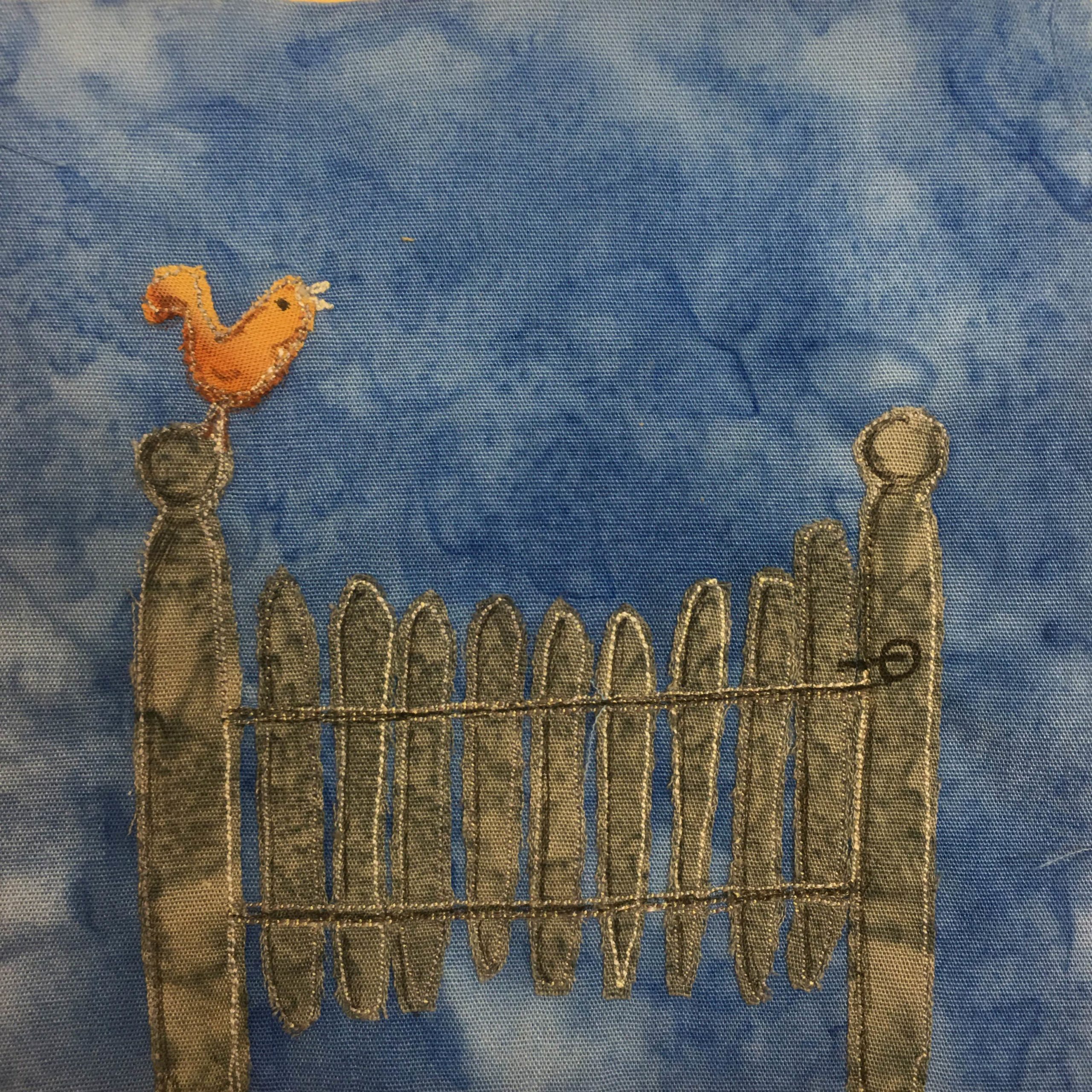 This block shows a metal gate with metal slats across it against a blue background. The gate itself has a little latch top open and close it. Each slat is gray and outlined with a light stitching. On each side of the gate is a post with a round spherical top. On the left post is an orange-yellow bird chirping.