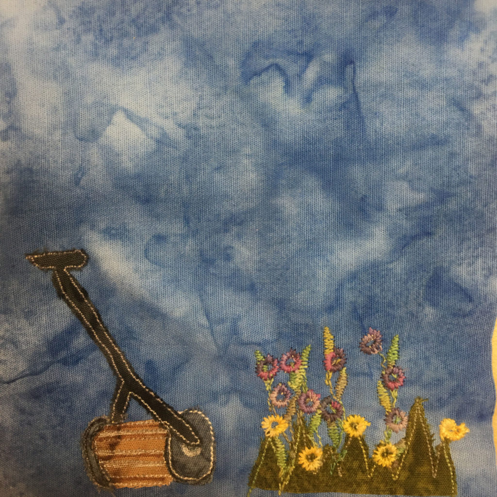 This quilt block shows a patch of weeds and grass with flowers both red and yellow in the lower right. This is made with a jagged cut of green fabric and quite a bit of multicoloreed stitching for the stalks and flwoers. To the left is a hand mower. This is a lawn mower you would push my hand. When you push it the wheel turns the blades inside the barrel of the machine's end that it cuts the grass. The handle and wheels of the mower are black with a yellow stitched outline. The blades inside area gold golden brown.