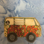 This quilt block shows a volkswagon microbus from the side. It has two huge wheels that are black, and inside each wheel is a hubcab with the VW logo penned in each gray piece of fabric. On the side of the bus in very stylized