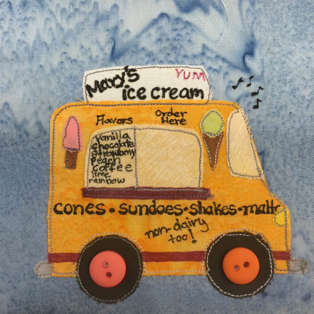 This quilt block shows an ice cream truck. The truck is very yellow with lots of writing on it. We are looking at it from the side. There are two big black wheels with two large colored two-holed buttons for the axles. One button is pink and one is orange. The truck is tall, and has a side window where orders can be placed. The windows is a lighter yellow and has writing on it with all the flavors. Next to the window are decals of ice cream cones. On the side of the truck under the window are the words, "Cones Sundaes Shakes Malts - non-dairy too!" The top of the truck has a white sign that reads, "Mary's Ice Cream - Yum." There are little notes in the air in the upper right part of the truck to show that it's making music.