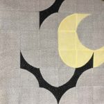 This image shows a fabric block with two stylized bats and a crescent moon.