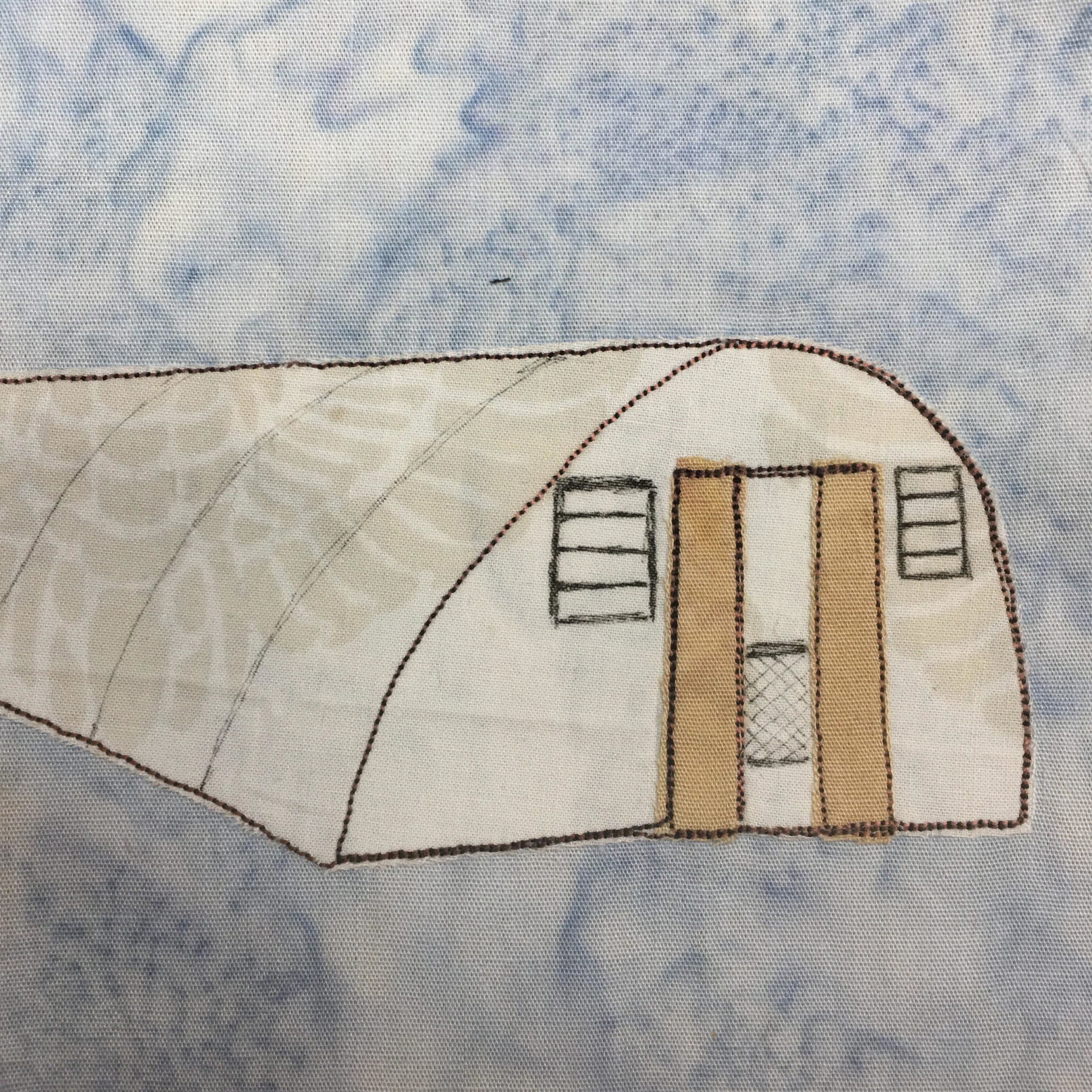 This quilt block shows a half-circle shaped building against a blue background. The half-circle is above the ground, with the lower half being below the ground if it were there. The front of the long structure has sliding tan doors in the middle. Next to the doors are two square sets of vents drawn in pen.
