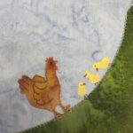 This quilt block is also a corner block. The corner is on the bottom right and is a large swatch of green fabric stretching from the bottom left corner to the upper right corner. On the curved surface of the grass is a mother hen, a cut out of brown fabric with pen marking and stitching on it to indicate the feathers and wing. Next to the mother hen are three small bright yellow patches of fabric shaped like baby chicks. Each baby chick has a little beak and eye in pen, and two tiny feet.
