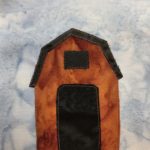 This quilt block shows a simple deep orange barn. It's very tall and has a tall and wide black opening for the entrance. The loft has an opening as well like a black window. The angular roof is also black.